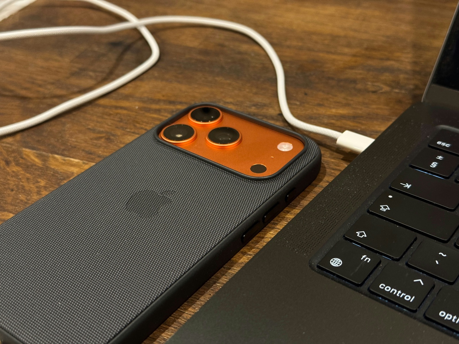 A smartphone connected to a laptop with a data cable